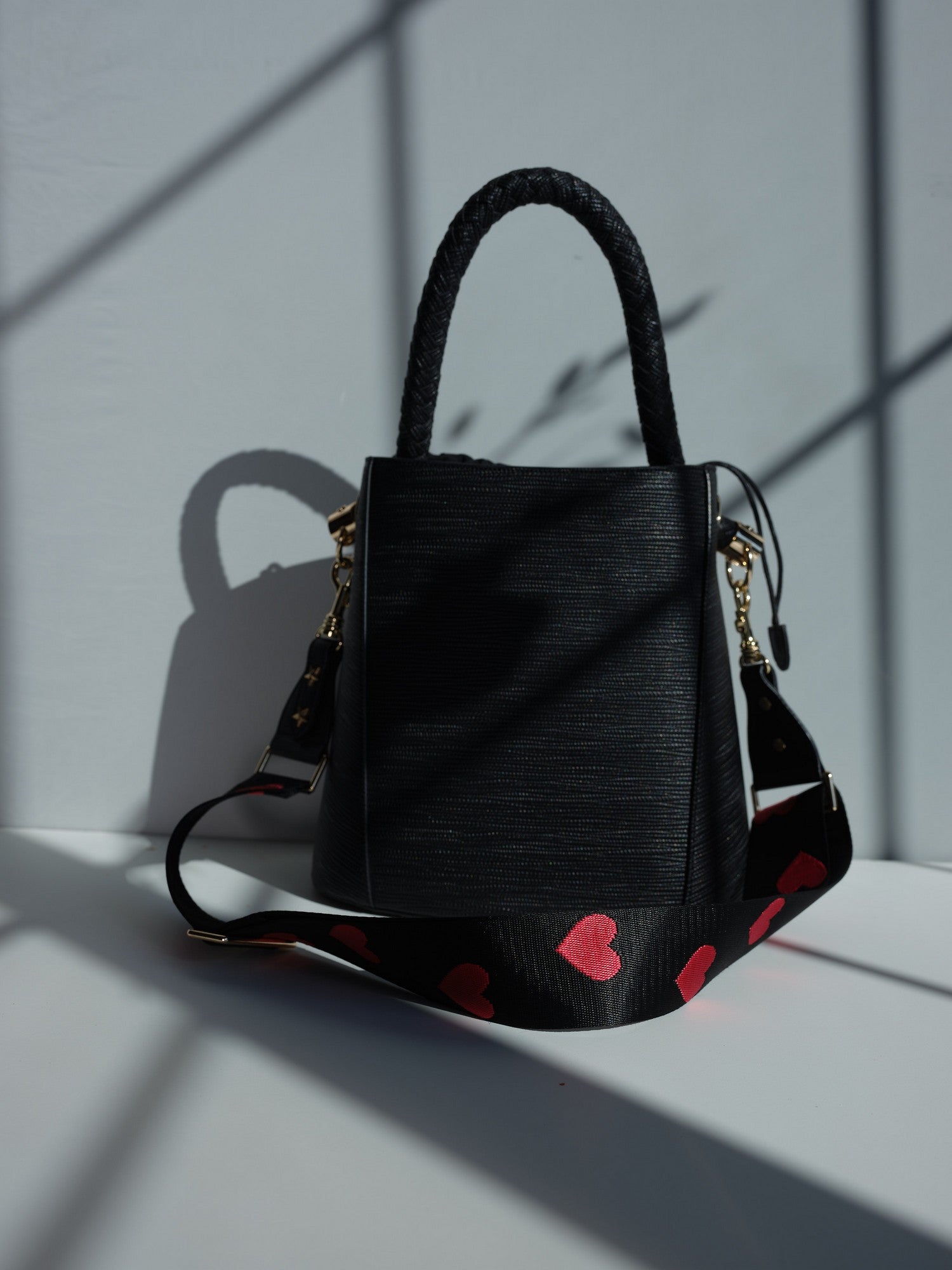 Large black vegan leather bucket bag with braided handle and shoulder strap