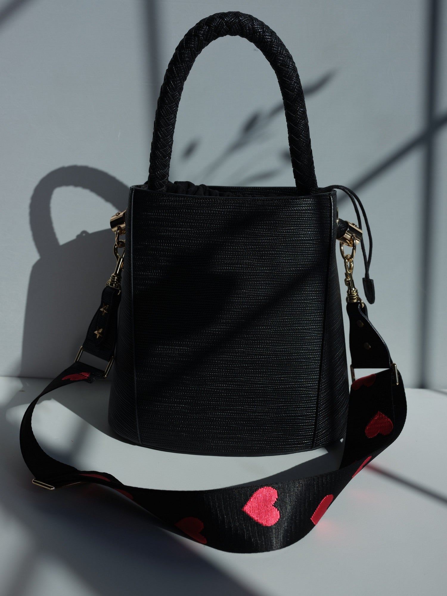 Large black vegan leather bucket bag with braided handle and shoulder strap